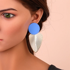 Détail de boucles d'oreilles avec clou bleu et pendentif en métal doré sur un modèle