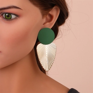 Détail macro de boucles d'oreilles géométriques vert mat et or sur un mannequin