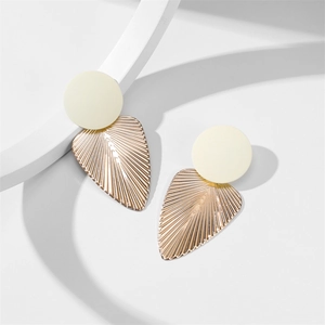 Détail de la boucle d'oreille dorée en forme de feuille avec texture radiale et bouton crème