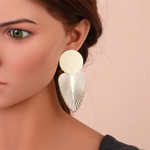 Détails macro de grandes boucles d'oreilles feuille dorées avec textures rayonnantes et cœurs