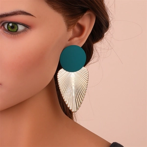 Gros plan sur des boucles d'oreilles feuille avec clous bleu sarcelle et pendentifs dorés