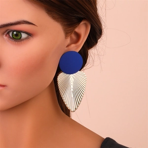 Détail de boucles d'oreilles disque bleu roi mat avec pendentif feuille dorée et rayures