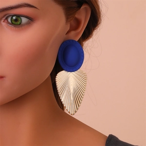 Détail des boucles d'oreilles pendantes en résine bleu marine et texture feuille dorée