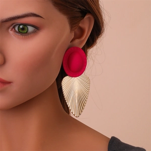 Gros plan d'une grande boucle d'oreille feuille rouge et dorée portée par un mannequin