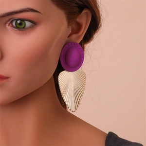 Détail de la boucle d'oreille avec puce ovale violette et pendentif en métal doré ciselé