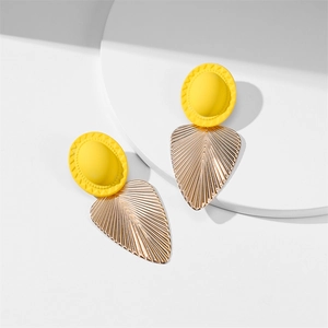 Vue détaillée du clou en résine jaune et du pendentif feuille dorée à texture brossée