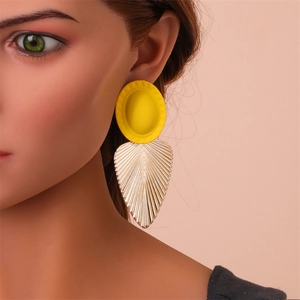 Détail de boucles d'oreilles feuilles géométriques avec clous jaunes mats sur mannequin