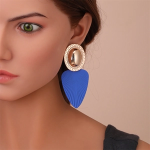 Gros plan de boucles d'oreilles pendantes en forme de feuille bleue avec détail doré