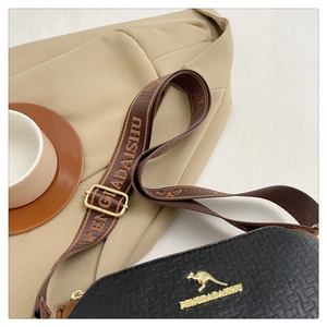 Close-up of black leather Boston bag with kangaroo logo and woven shoulder strap