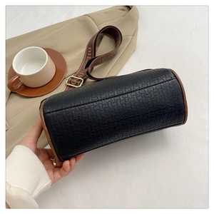 Detail of black cylinder bag with woven texture and decorative jacquard strap