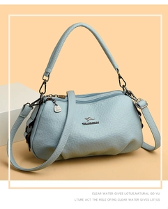 Détail du sac à main bleu clair texturé avec logo en métal et breloque kangourou