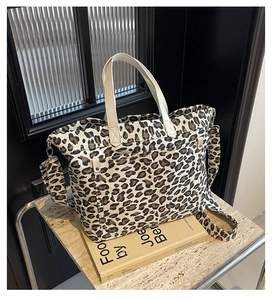 Close-up of leopard print canvas tote bag with cream handles on marble surface