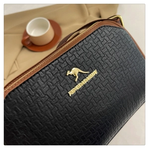 Close-up of black textured woven leather Boston bag with brown trim and gold logo