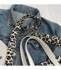 Detail of adjustable leopard print strap with white leather piping and silver buckle