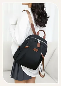 Detailed view of black nylon backpack with brown leather accents worn by a model