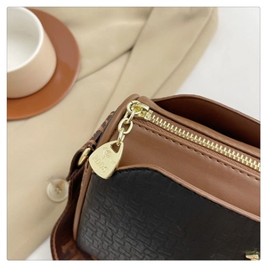 Detail of golden zipper and kangaroo pendant on brown and crocodile pattern leather bag