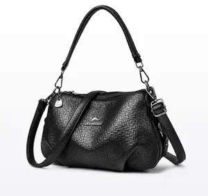 Détail de la texture cuir grainé noir du sac bandoulière avec emblème kangourou argenté