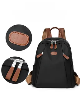 Detail of black nylon backpack featuring contrast brown trim and silver metal double zippers