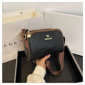 Detail of black and brown leather crossbody bag featuring gold logo and woven pattern