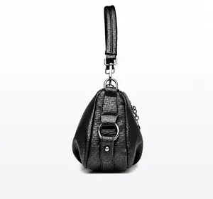 Détail du sac à main en cuir grainé noir montrant le profil latéral et les boucles en argent