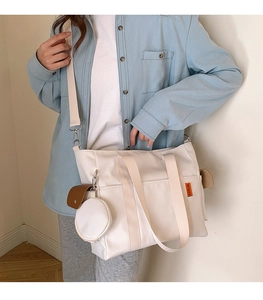 White nylon tote bag with orange label, adjustable strap and detachable round coin purse