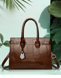 Detail showing brown lychee leather stitching and gold hardware on large tote bag
