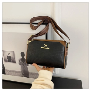 Detail of cross-body bag featuring a gold kangaroo logo and jacquard fabric strap
