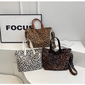 Three leopard print tote bags in different colors displayed on modern white pedestals