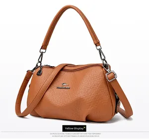 Détail du sac à main en cuir grainé jaune avec logo métallique et bandoulière réglable