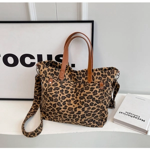 Detailed shot of leopard print canvas tote bag with brown leather handles and wide strap
