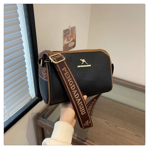 Close-up of black pebble leather shoulder bag with gold kangaroo logo and brown trim