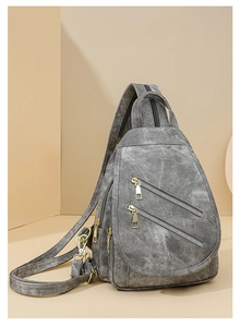 Detalle de bandolera gris lavado con cremalleras dobles paralelas y herrajes dorados
