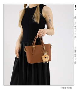 Detail of brown lychee leather bucket bag with a plush dog charm and gold hardware