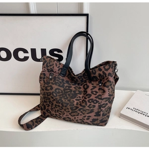 Detail of leopard print canvas tote bag featuring premium texture and black leather handles