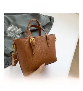 Detail shot of brown lychee texture handbag with elegant gold metal hardware buckles