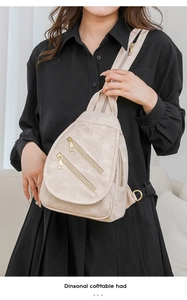 Detalle del bolso de pecho de cuero crema con cremalleras doradas llevado por modelo