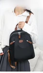 Detailed back view of a black nylon backpack featuring brown straps and leather accents