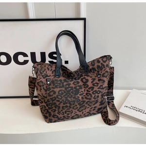 Detailed view of leopard print canvas tote with detachable wide strap and metal D-ring studs
