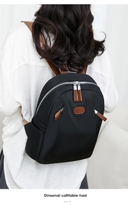 Close-up of minimalist black nylon backpack with brown leather tags and silver zippers