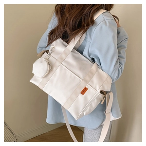 White nylon tote bag on shoulder showing large capacity and orange side label detail