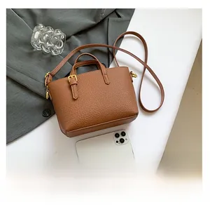 Close-up of caramel brown lychee leather handbag with smartphone for size comparison