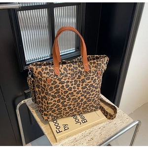 Detail of leopard print tote bag with brown faux leather handles and wide shoulder strap