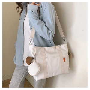 Detail of white nylon tote bag with wide strap and round coin purse accessory