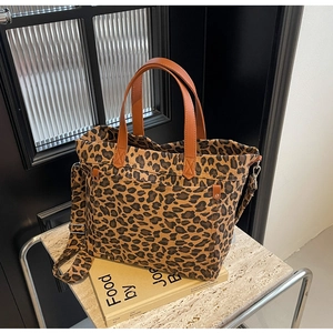 Detail of leopard print canvas tote with brown leather handles and multi-pocket design