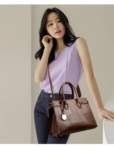 Detail view of large dark brown leather tote bag with stylish patchwork stitching
