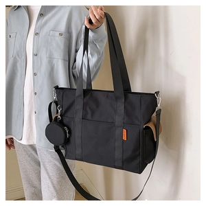 Close-up of black nylon tote bag featuring a detachable shoulder strap and small round coin purse