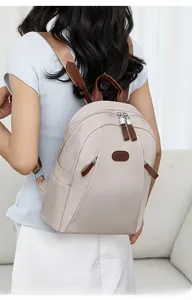Detail view of the beige nylon backpack showing ergonomic back fit and leather strap accents
