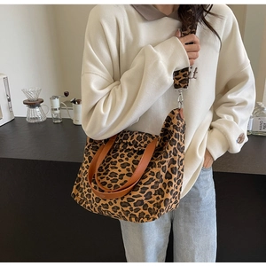 Leopard print canvas tote bag with adjustable wide strap shown worn over the shoulder