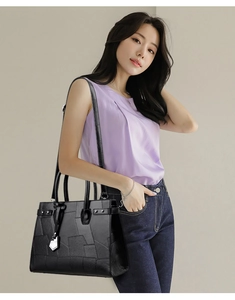 Detail of black leather tote bag featuring geometric patchwork and silver hardware