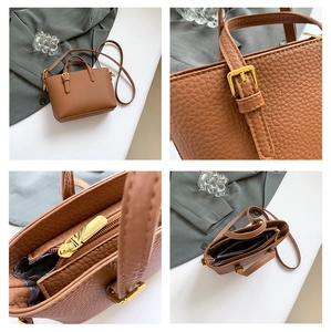 Detail view of brown lychee leather texture and golden metal hardware on a bucket bag